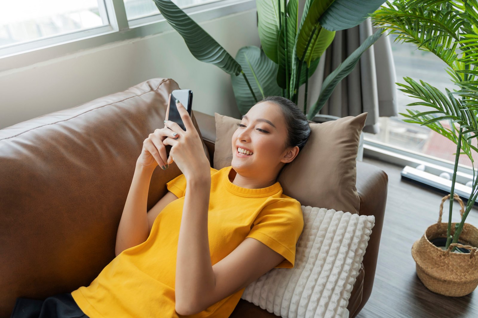happiness-cheerful-smiling-young-adult-asian-female-woman-wear-yellow-cloth-hand-conversation-smartphone-sofa-home-remote-quarantine-lock-down-period-home-interior-background