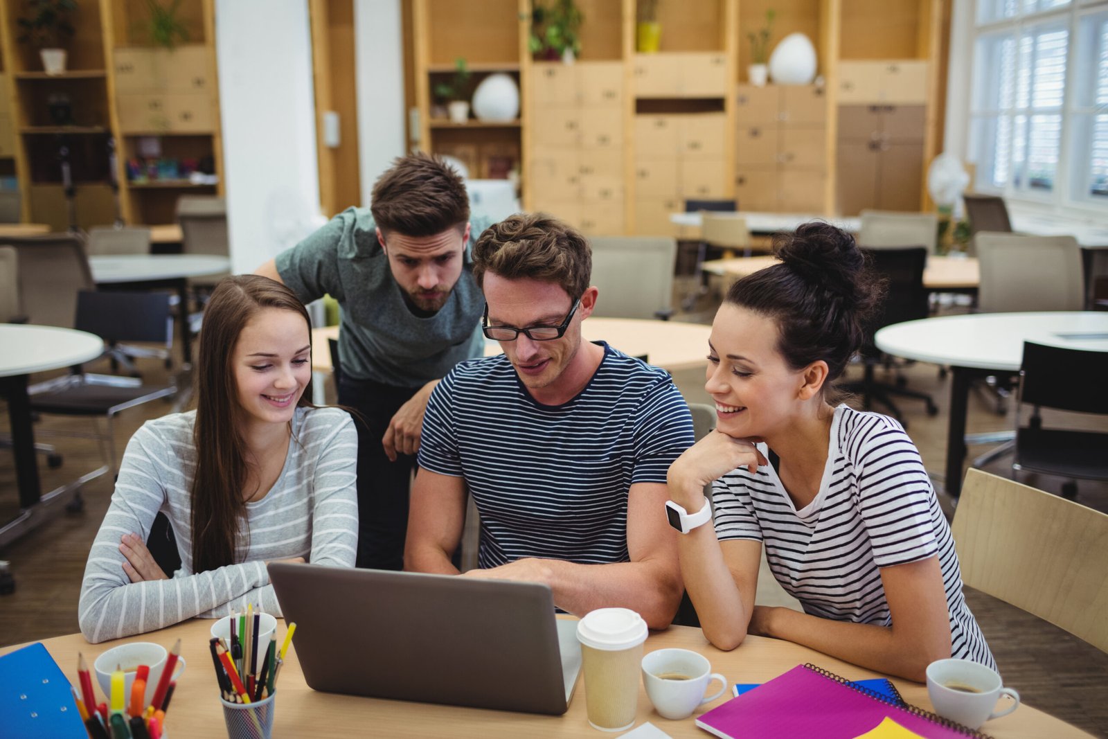 Group of business executives discussing over laptop at their desk